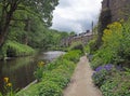 Canal path surrounded by summer flowers with a row of old stone houses at eastwood in hebden bridge west yorkshire Royalty Free Stock Photo