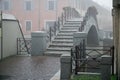 Canal and a pedestrian bridge, foggy weather in Italy