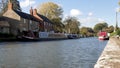 Canal river with moored boats and shop around it in village in northamptonshire, england