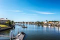 Canal in tropical setting with boat docks and moored boats by each waterside house and palm trees under blue sky Royalty Free Stock Photo