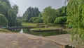 A canal with water runs through the city park. The banks of the canal are concreted and have stairs built into them that lead to t