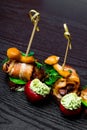 Canape, rolled bacon, tomatoes with cream pesto, honey agaric on wooden table, holiday appetizing