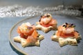 Canape sandwiches in star shape with shrimps and salmon on a blue plate, finger food snack for a festive holiday party like Royalty Free Stock Photo