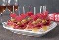 Canape for Valentines Day with hearts from cheese, olives and sausage on white plate shaped-heart and two glass rose