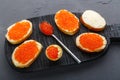 Canapes with butter and red caviar next to a spoon with caviar on a wooden board on a concrete background Royalty Free Stock Photo