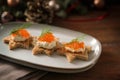 Canapes with red caviar, cream and dill garnish on toasted bread in star shape on a gray plate, dark rustic wooden table with