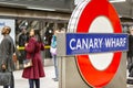 Canary Wharf underground sign with commuters waiting on a platform in the background Royalty Free Stock Photo
