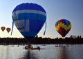 Kayakers watching big colourful hot air balloons