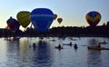 Kayakers watching big colourful hot air balloons