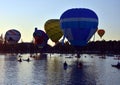 Kayakers watching big colourful hot air balloons