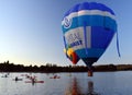 Kayakers watching big colourful hot air balloons