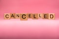 CANCELLED word made with building blocks, business concept. Word CANCELLED on pink background. Global mass gathering