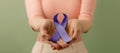 Cancer Awareness Campaign Concept. Global Healthcare. World Cancer Day. Close up of a Young Female Holding a Violet Ribbon into