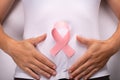 Cancer fighting symbol. girl holding a pink ribbon on her stomach, uterine cancer