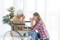 Cancer patient, caucasian old woman wearing a head scarf, sitting in a wheelchair, and her daughter praying together. Cancer Royalty Free Stock Photo