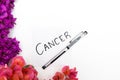 Cancer word written on note with pen and wild purple and pink flowers. Royalty Free Stock Photo