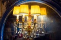 Candelabrum with a yellow lampshade with glass elements on an old mirror.