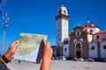 Candelaria, Santa Cruz de Tenerife, Spain - 15.05.2018. Young, confused woman tourist holds in her hands map of the city against