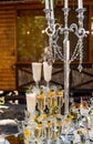 Candelstick and three vertical lines of crystal champagne glasses. Rich and fashionable decoration. Closeup.