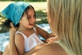 Candid closeup portrait of a happy daughter haveing fun wioth her mother sitting on the blanket in the park on a sunny summer day