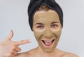 Candid closeup portrait of happy young woman indicate with finger on her cosmetic green clay organic mask on her face, wears black Royalty Free Stock Photo