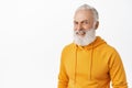 Candid happy old man with long stylish beard, laughing and smiling, looking happy, wearing modern orange hoodie