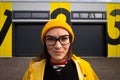 candid head shot of a caucasian woman wearing glasses and a yellow cap looking into the camera Royalty Free Stock Photo