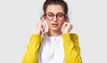 Candid horizontal shot of brunette pretty young woman using mobile phone to listening the music. Beautiful female enjoy the songs Royalty Free Stock Photo