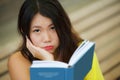 Candid lifestyle portrait of young beautiful and relaxed Asian Korean student girl on reading book or studying outdoors at coffee Royalty Free Stock Photo