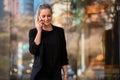 Candid lifestyle portrait of stylish female business woman talking on a cellphone while walking in city with a cheerful smile Royalty Free Stock Photo