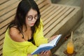 Candid lifestyle portrait of young beautiful and relaxed Asian Korean student girl on reading book or studying outdoors at coffee Royalty Free Stock Photo