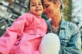 Candid outdoors portrait of young woman smiling and embracing her little cute daughter, spending time together. Mother with her Royalty Free Stock Photo