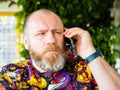 Candid photo of adult worried bearded man talking by smartphone