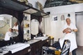 Candid photograph of an old-fashioned barber cutting a man\'s hair in his shop