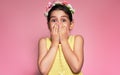 Candid portrait of an astonished little girl wearing a yellow dress covering her mouth with hands receiving a gift at her birthday Royalty Free Stock Photo