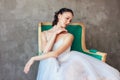 Candid portrait of Ballet dancer ballerina in beautiful light blue dress tutu skirt posing sitting on vinage chair in loft studio Royalty Free Stock Photo