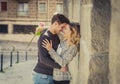 Candid portrait of beautiful European couple with rose in love kissing on street alley celebrating Valentines day Royalty Free Stock Photo