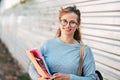 Candid portrait of a female student carrying lots of books after a day in the college. Beautiful young woman smiling dressed in a Royalty Free Stock Photo