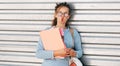 Candid portrait of a funny female student in transparent eyeglasses carrying lots of books after a day in the college and making