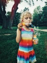 funny little blonde Caucasian child girl blowing soap bubbles in park at summer sunset Royalty Free Stock Photo