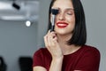 Candid portrait of a gorgeous brunette female with red lips posing with a brush after making make-up tutorial. Happy young woman Royalty Free Stock Photo