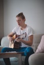 Candid portrait guy sitting on grey sofa hold acoustic instrumental guitar playing new written song sound signing creative