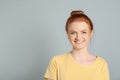 Candid portrait of happy red haired woman with charming smile on light grey background, space for text