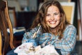 Candid portrait of a happy young woman with blots on her face smiling and looking directly to the camera after painting on canvas Royalty Free Stock Photo