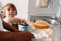 Candid portrait of little girl helps her mother to prepare cookies. Cute kid with flour in kitchen Royalty Free Stock Photo