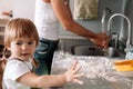 Candid portrait of little girl helps her mother to prepare cookies. Cute kid with flour in kitchen Royalty Free Stock Photo