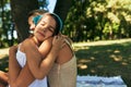 Candid portrait of a loving mother hugging tenderly her little daughter sitting on the blanket in the park on a sunny summer day. Royalty Free Stock Photo