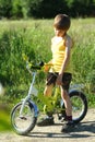 Candid portrait of an upset boy with a bicycle in the sunlit field