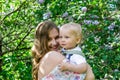 Candid portrait of young smiling mother with her little son in garden with blooming lilac flowers Royalty Free Stock Photo