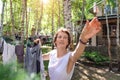 Candid real life portrait of young adult beautiful attractive caucasian woman hanging up fresh washed family clothes on birch tree Royalty Free Stock Photo